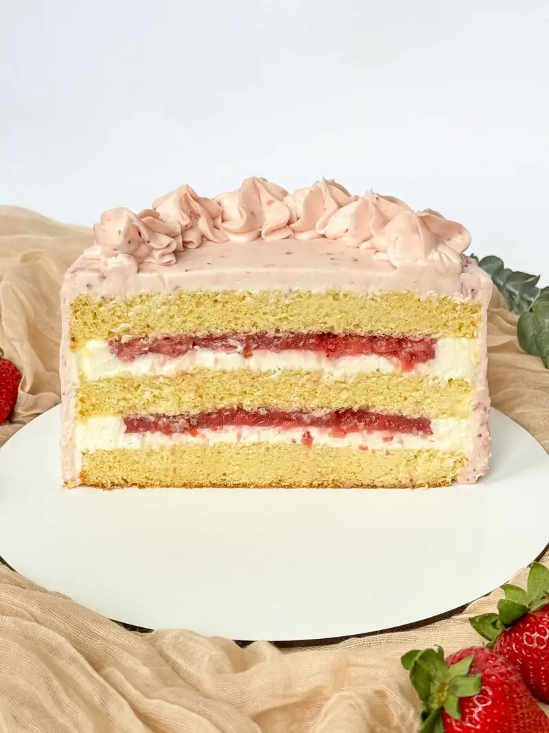 half of vanilla strawberry cake on the cake board Active Image